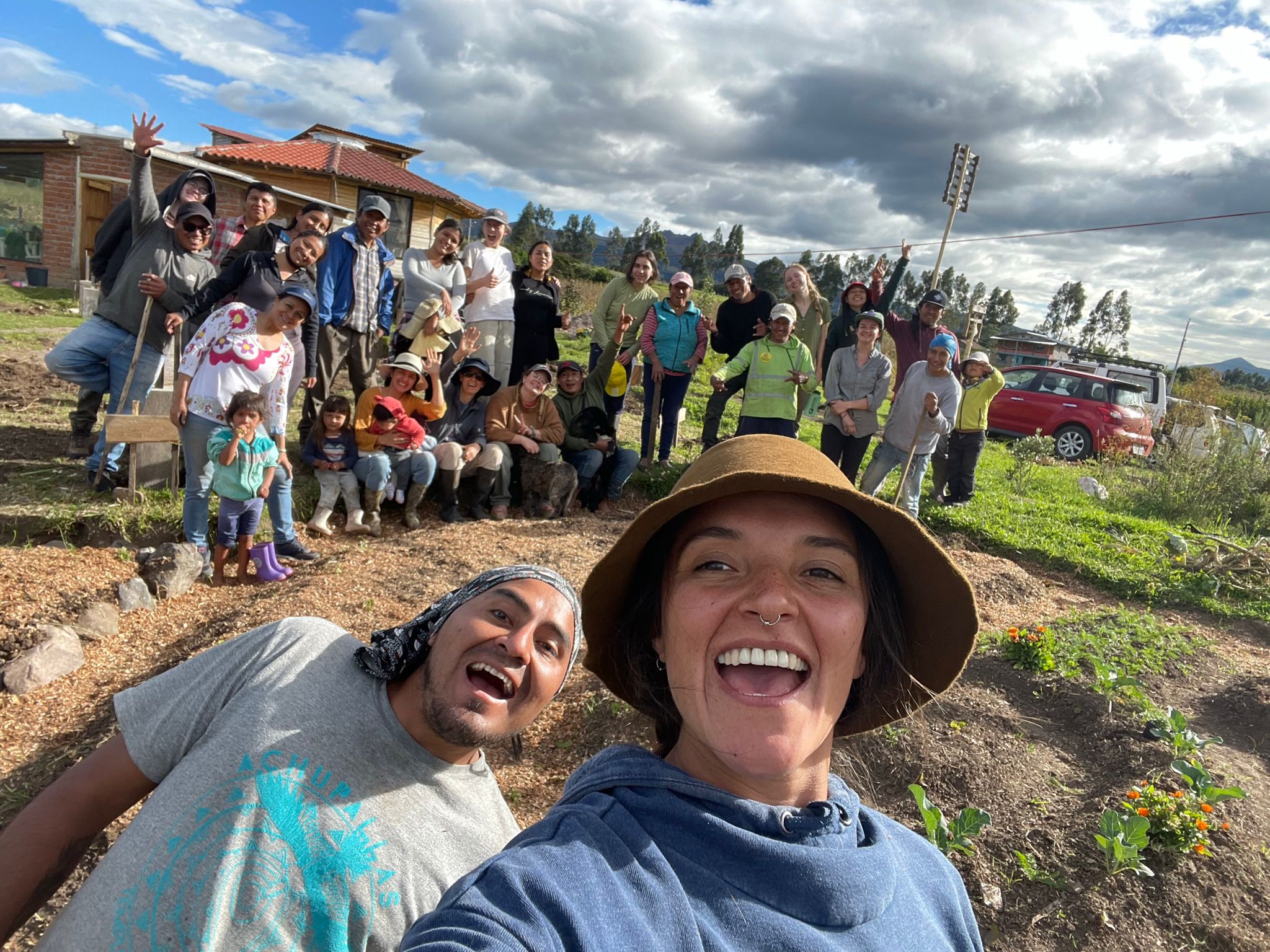 Chel taking a selfie with around 15 people who are all holding tools after a day of collective work. 